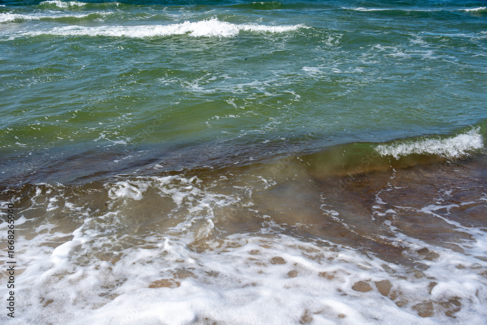 Obraz premium Sea waves green water stormy blue sky beach sand textures