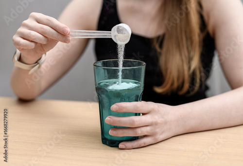 A woman dissolves a scoop of creatine powder in water to drink.