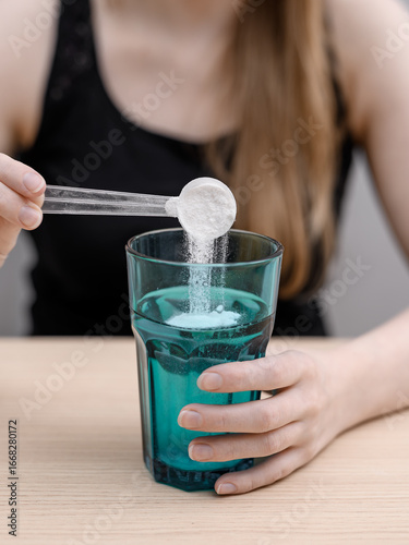 Woman dissolving a scoop of collagen powder in water, drink collagen