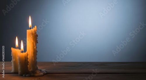 Warm glow of three melted wax candles on a wooden table against a soft blue background, creating a peaceful atmosphere.