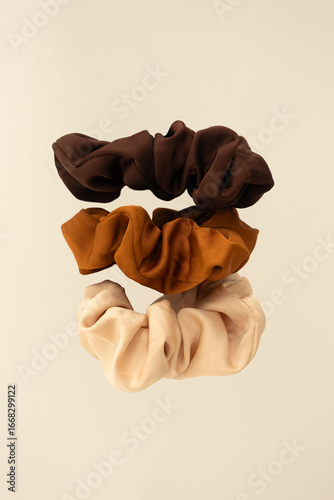 Set of neutral satin scrunchies levitation. Hair care and accessories concept  