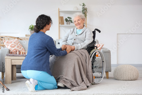 Young African-American female medical worker with elderly woman on wheelchair...