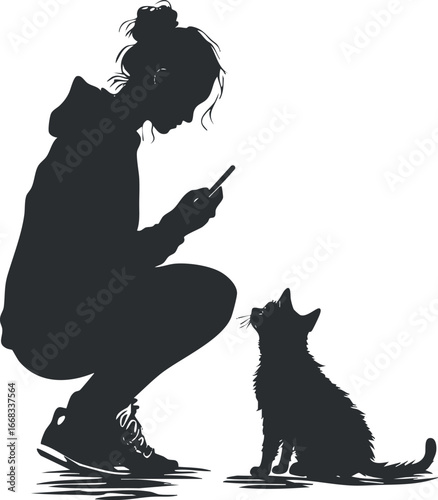 Silhouette of a young woman squatting while using a smartphone interacting with a sitting cat