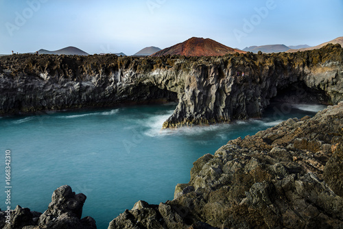 Turquoise water crashing against volcanic cliffs in los hervideros, lanzarote