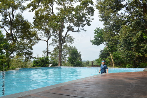 An Asian boy playing at the narrow side on the forest infinity pool