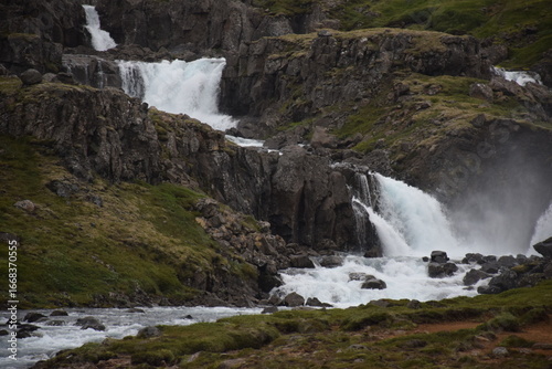 Majestic waterfall cascading over rocky cliffs into a river.