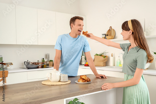 Young couple eating croissa...