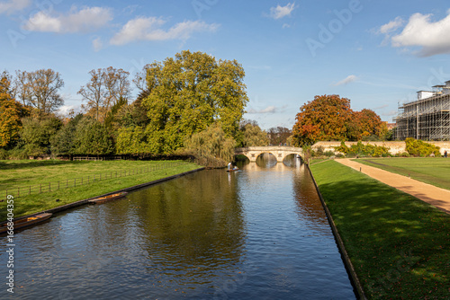 Cambridge, England. Gardens and walkways of King's College with autumn foliage, the River Cam, and punts moored along the riverbank beside the historic college grounds