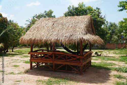 Obraz na plátne A rustic bamboo hut with a thatched roof sits in a tranquil outdoor setting