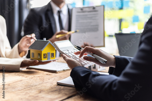 Photos Real estate agent calculates property value with customer, discussing investment potential surrounded by paperwork