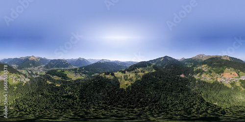 фотографія 360 degrees aerial panorama of mountain slope with green meadows and pine tree divide with cloud obscuring half of the scenery