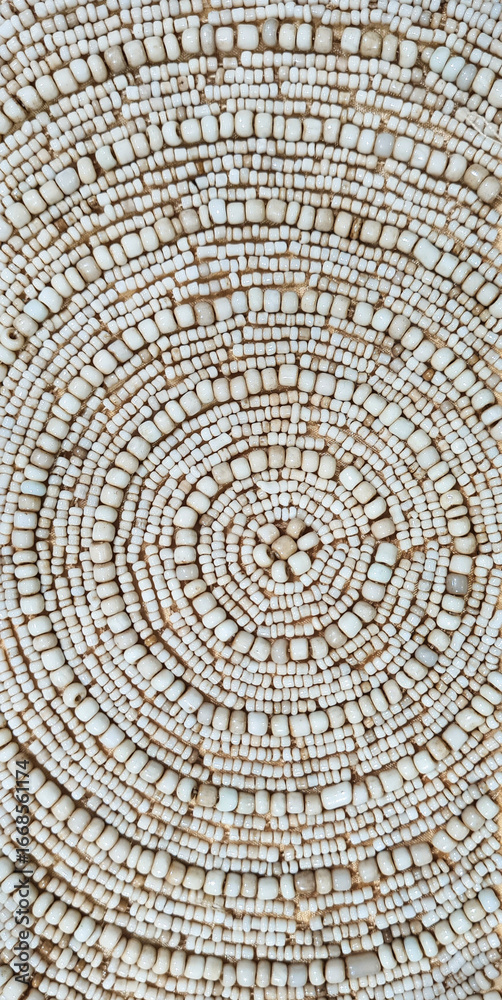 Fototapeta premium Background of circular pattern on ivory beads, up close. Traditional handicraft of ivory beads with circular pattern for decoration.