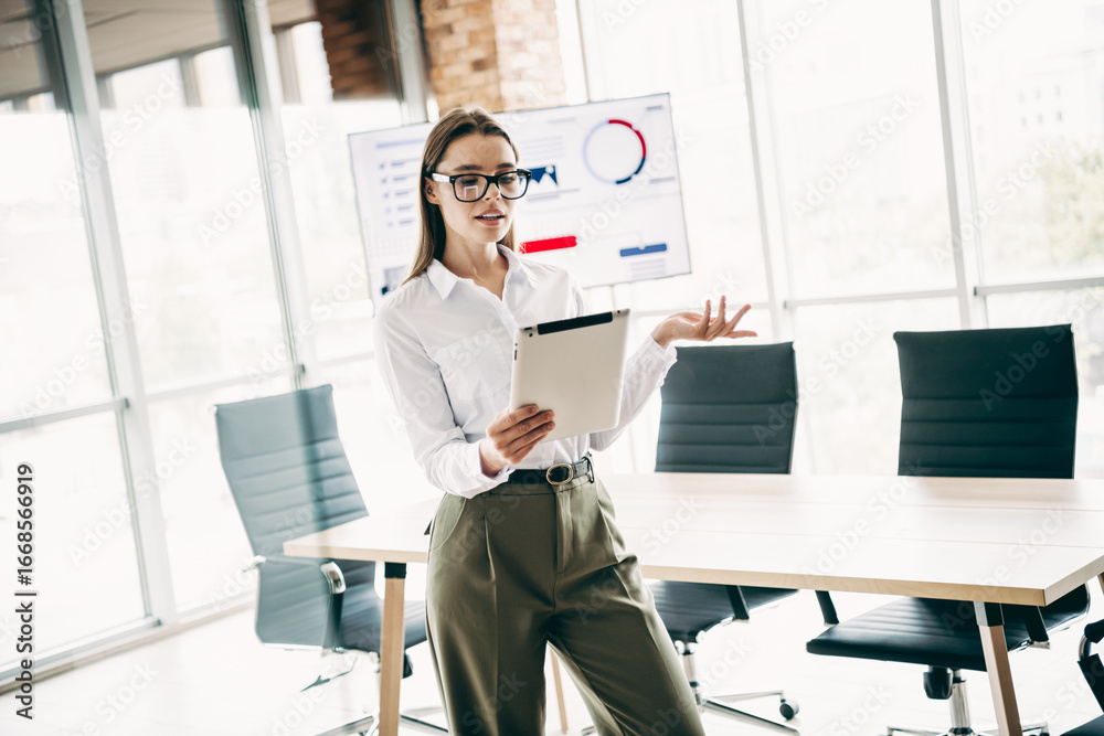Fototapeta premium Qualified businesswoman presenting a project in a modern office workspace with professional documents and data visuals displayed