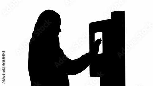 Silhouette of a woman interacting with a touch screen kiosk in a public space at an automated machine
