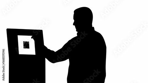 Silhouette of a man interacting with a qr code display on a kiosk in a high contrast black and white image