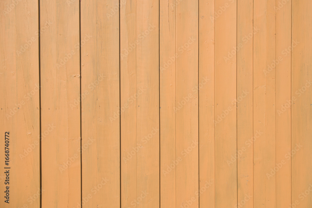 Naklejka premium Vertical wooden boards painted in a light tan color form a smooth, uniform fence surface under direct sunlight.