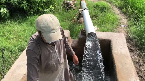 Man working on water pipe in grassy area
