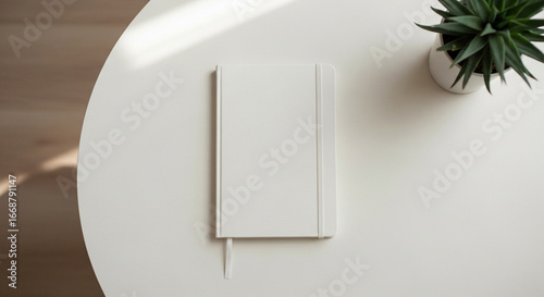 Get organized with this elegant white notebook and stylish succulent on a modern round table top