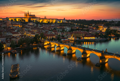 Obraz na plátně Breathtaking drone panorama of Prague at sunset, featuring Prague Castle and Charles Bridge glowing in golden light over the Vltava River, blending history and beauty from above