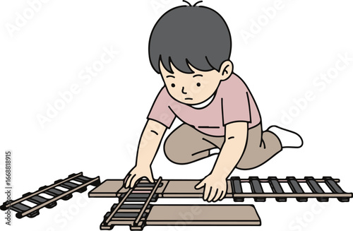 A focused young boy with black hair, wearing a pink shirt, kneels on the floor to assemble a wooden toy train track.