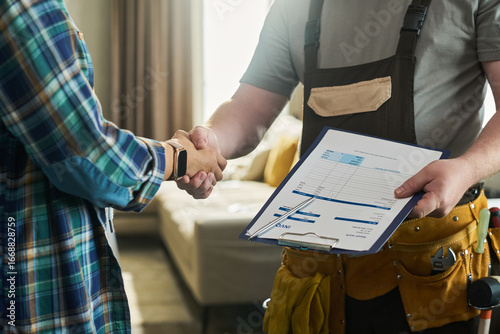 Tableau sur toile Caucasian middle aged man wearing tool belt holding invoice clipboard shaking ha