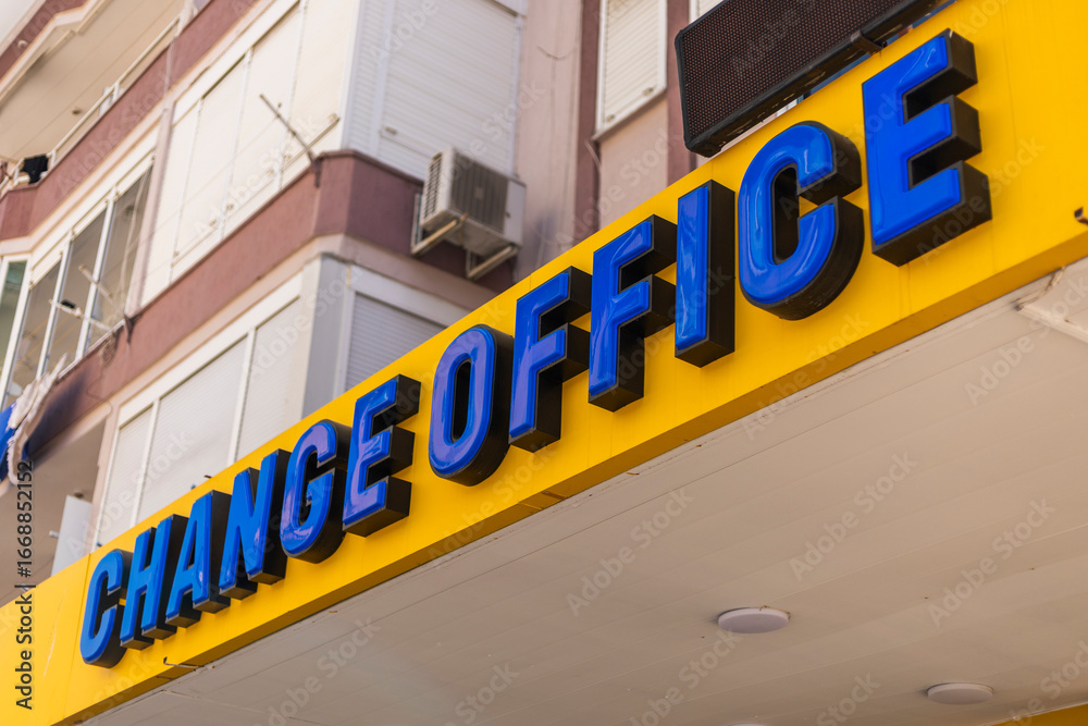 A vibrant yellow sign reading CHANGE OFFICE catches attention in an urban location A vibrant yellow sign reading CHANGE OFFICE catches attention in an urban location