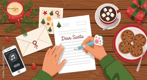 Overhead view of hands writing a "Dear Santa" letter on a wooden desk with Christmas decorations, cookies, hot chocolate, and a smartphone.