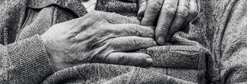 Elderly hands joined in a tender gesture, wedding ring visible, black and white fine art photograph. Universal portrait of love, resilience, and the passage of time in Beaune, Burgundy, France