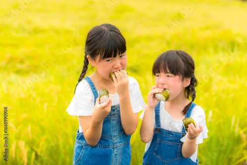 田んぼの前でおにぎりを持つ姉妹