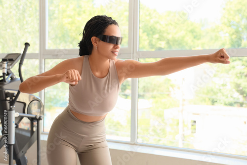 Sporty African-American woman in VR glasses training at gym Free Download Sporty African-American woman in VR glasses training at gym - GFXLoad