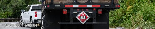 Flammable Liquid caution sign with flame symbol and code for UN 1263, Hazard Class 3 warning on the back of a city public works painting truck
