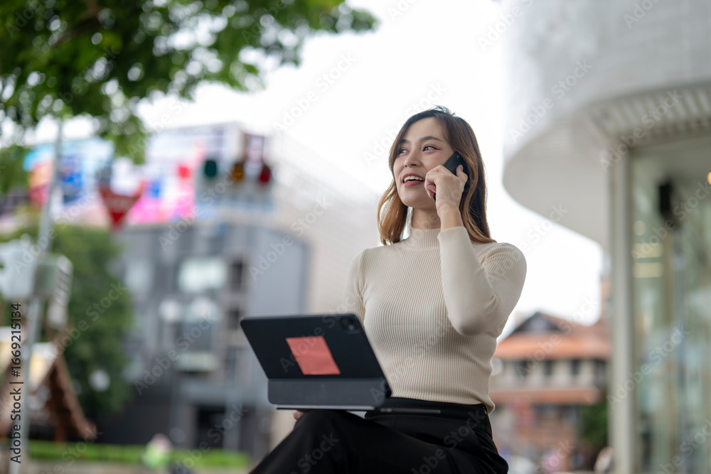 Fototapeta premium woman is talking on her cell phone while sitting on a bench