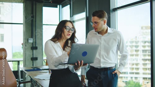 Business colleagues arguing about something while working together in a modern office with large windows and a scenic view.
