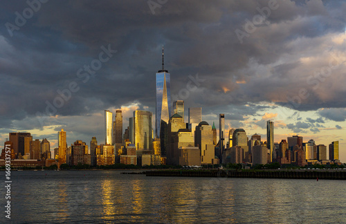 New York city. NYC cityscape. Lower Manhattan and One World Trade Center in New York Cit. Skyscrapers of Manhattan located near rippling water of New York bay against blue sky. New York skyscrapers.