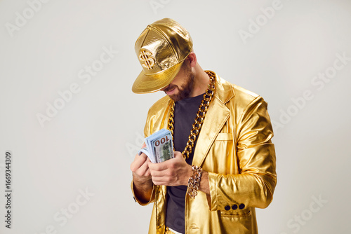 Quadro em tela A rich man in a gold jacket holds a wad of dollars, close-up