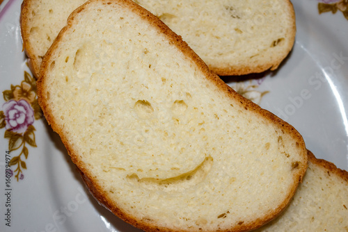 Smiling piece of bread lies on a plate, effect of pareidolia or apophenia