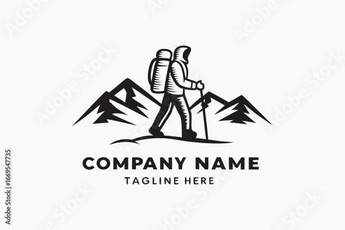 Silhouette hiker with backpack treks atop mountainous terrain using a hiking stick for support