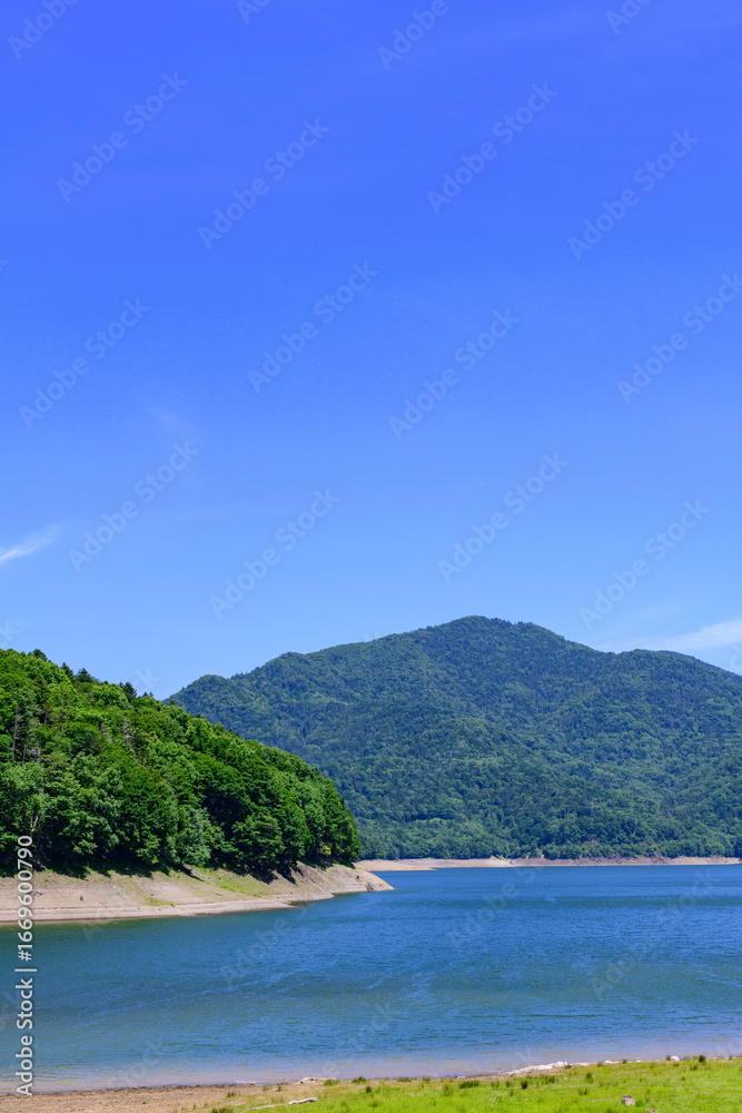 Fototapeta premium Nukabira River Bridge with Nukabira Lake, River and Dam under July Blue Sky, Hokkaido Japan