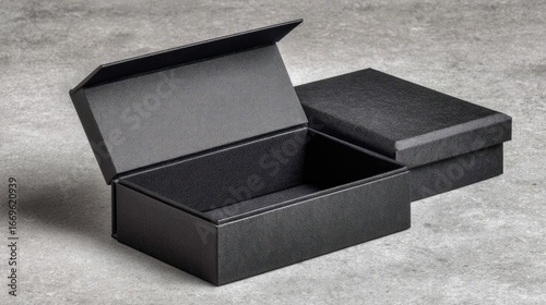 Two black boxes, one open, on a gray surface