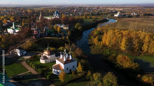 Kamenka river, autumn landscape of suzdal, churches and colorful trees at sunset