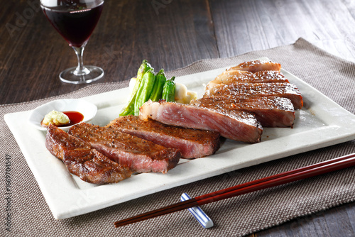 お箸で食べるカットした黒毛和牛サーロインステーキとワイン