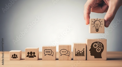 A hand places a lightbulb symbol block atop a series of wooden blocks depicting collaboration, communication, and innovative thinking.
