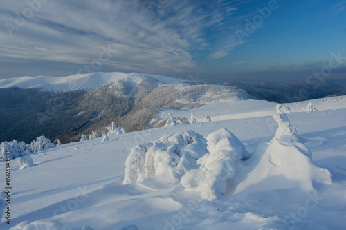 View of a serene winter landscape draped in pristine snow under a sky streaked with wispy clouds in Velka Fatra mountains,  BelÃ¡-Dulice, Å½ilina Region, Slovakia.