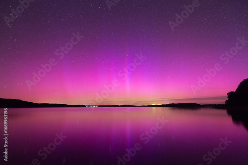 Fotografie the purple lights of the aurora borealis reflecting in the lake's surface