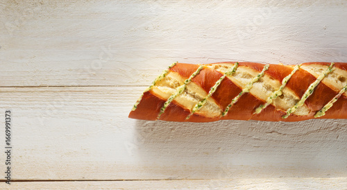 Laugen Baguette mit geschmolzener Kräuterbuttter auf rustikalem hellem Holzfond