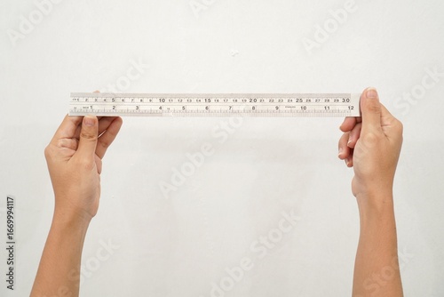 Papier peint Women Hand holding a stainless steel ruler on isolated white background