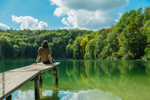 Tableau sur toile Frau sitzt auf einem Steg am See beim Jezioro Szmaragdowe, Smaragdsee, in Stetti