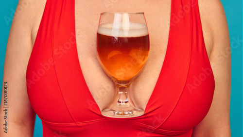 Konstfotografi Close up of beer glass placed in red dress cleavage on blue background