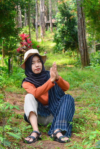 Young Asian Muslim woman hiking and camping in autumn forest, smiling at camera wearing Javanese ethnic clothes