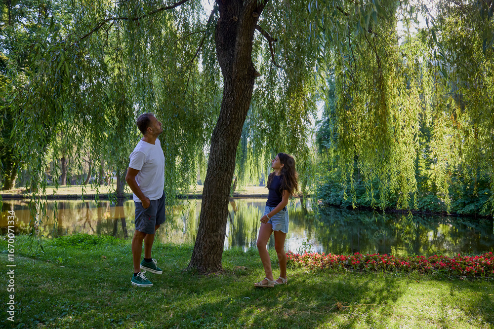Fototapeta premium Father and daughter in the park on a summer morning spending time together enjoying nature.